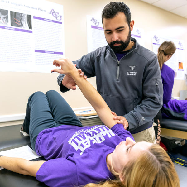 A kinesiology major student lifting another student’s arm
