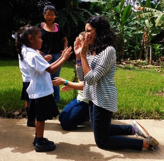 Renique Rodriguez kneeling with a child