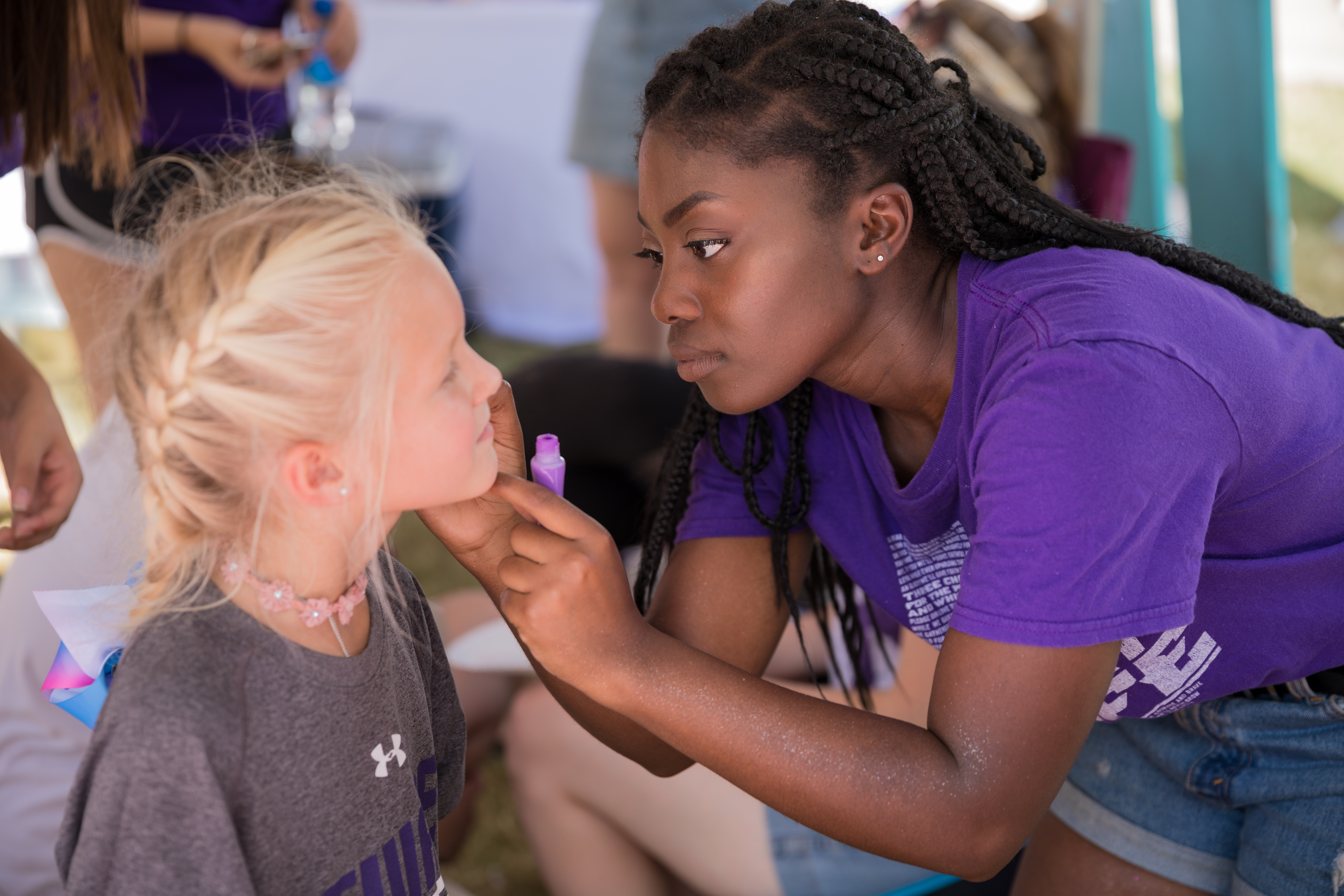 Eboni Childs, a senior member of Tri Kappa Gamma, paints the face of a Wildcat fan during a tailgate last fall.