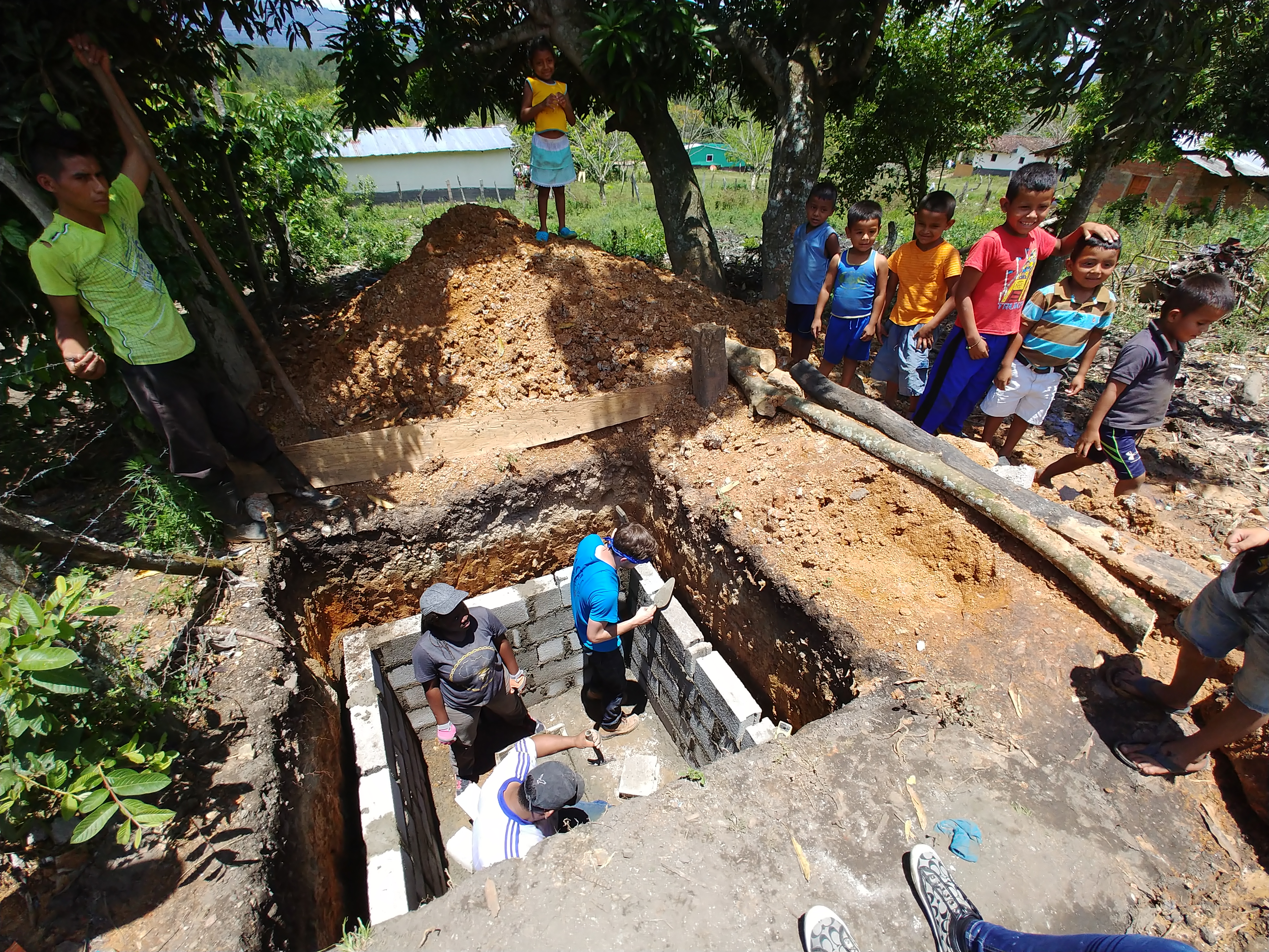 Children in the village of Linares, Honduras, watch ACU engineering and physics students construct latrines they designed as a class project.