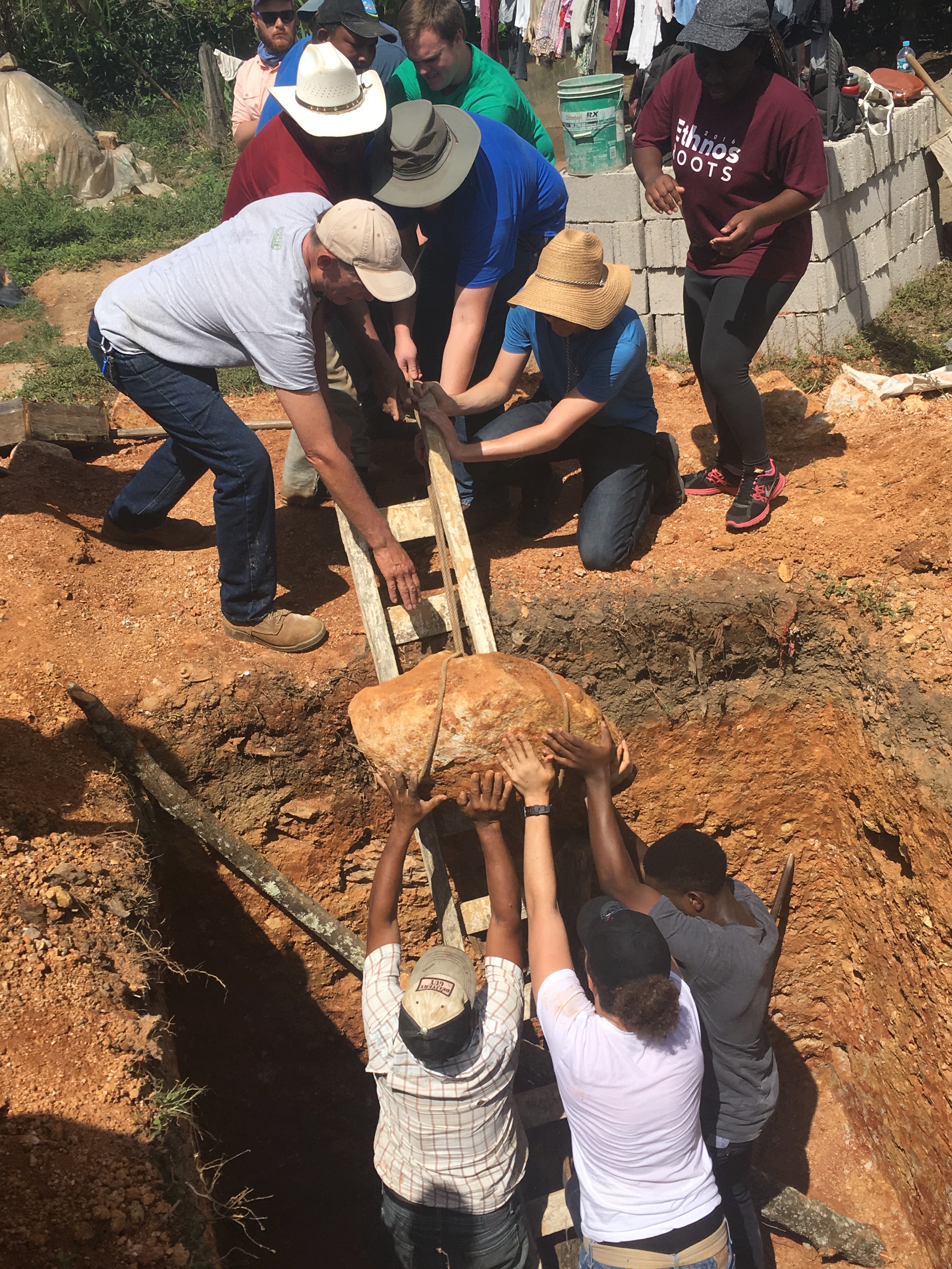 ACU engineering and physics students work with a family in Linares to "engineer" a solution to get a large rock out of the latrine pit before beginning construction. 