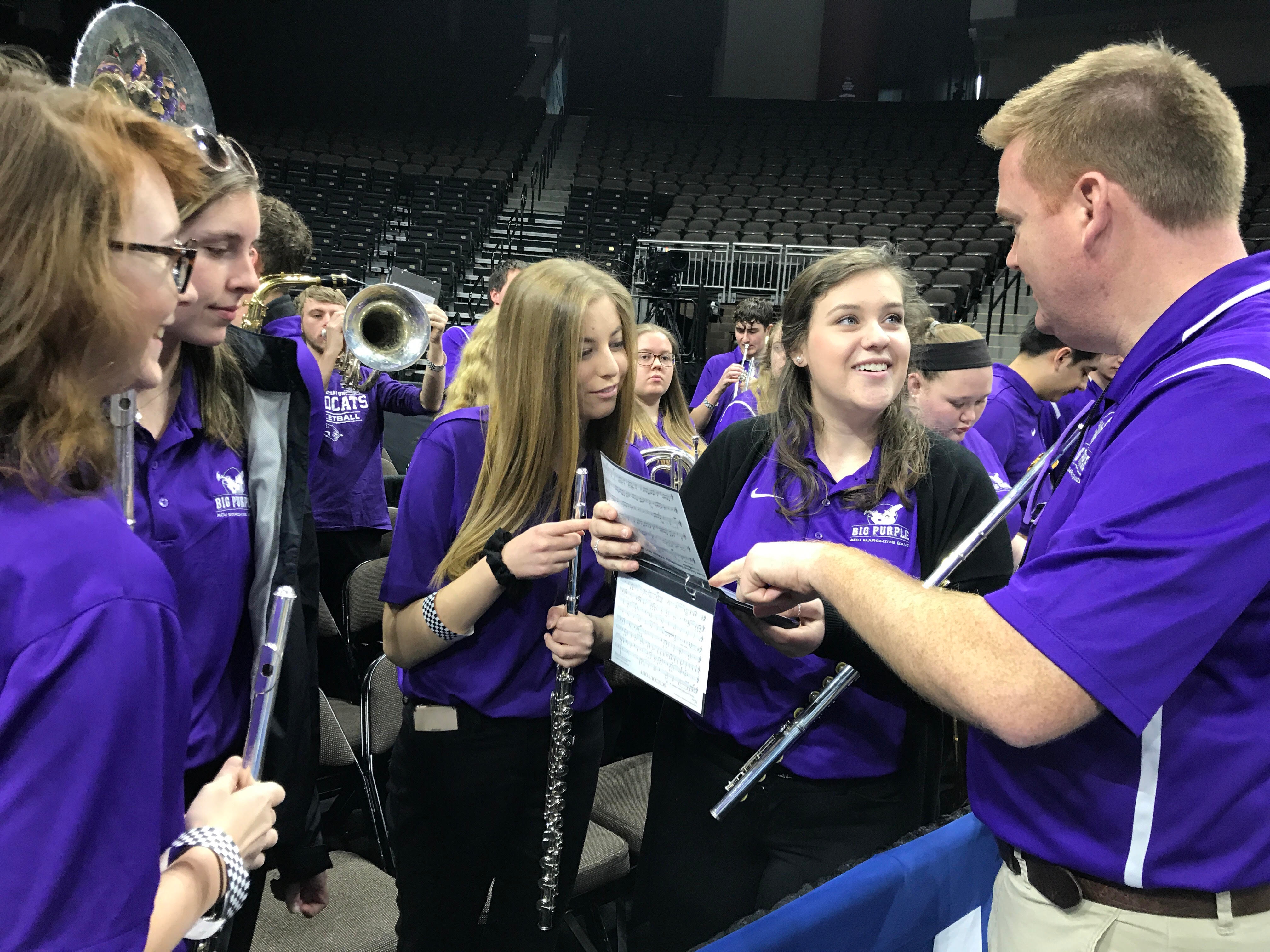 At a practice session in the arena on Wednesday in Jacksonville, (from left) Emily Tiras, Faith Parsons, Bailey McCall and Alli Mae Bulkley discuss music selections for the upcoming game with Dr. Brandon Houghtalen (right).