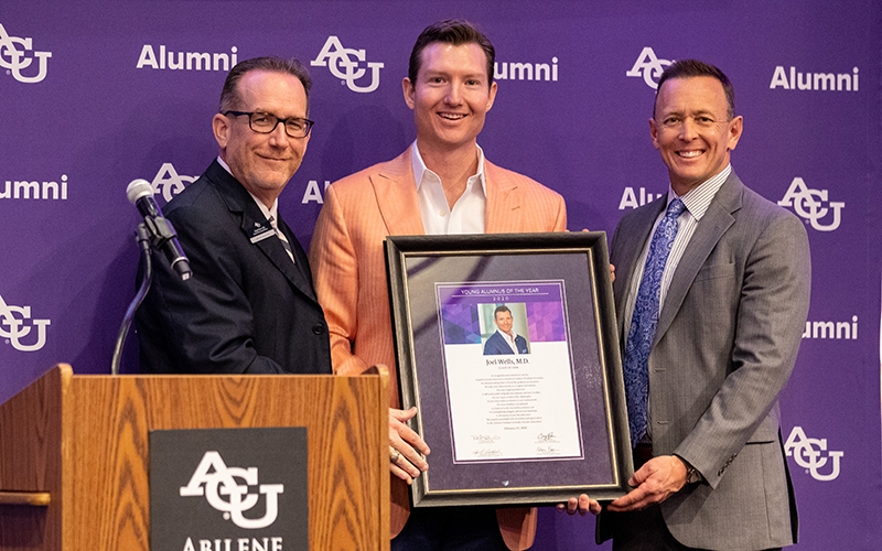 Joel Wells, M.D. ('06), is presented his 2020 Young Alumnus of the Year Award by Craig Fisher (left), and Dr. Phil Schubert.