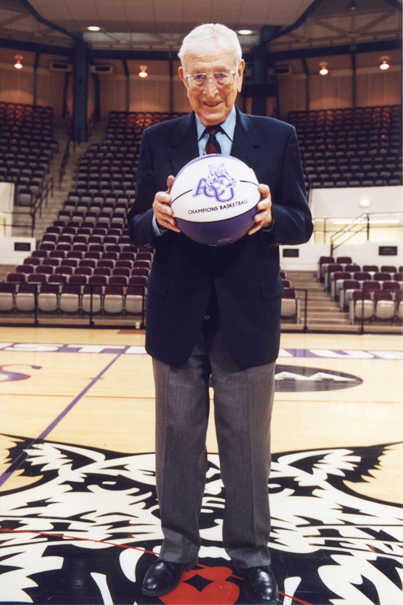 John Wooden poses at center court in Moody Coliseum in 2000 during one of his speaking engagements on campus.